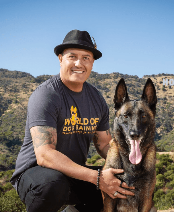 Ryan Matthews, U.S. Army veteran and founder of World of Dog Training, kneeling with his Belgian Malinois on a hillside overlooking the Hollywood Hills